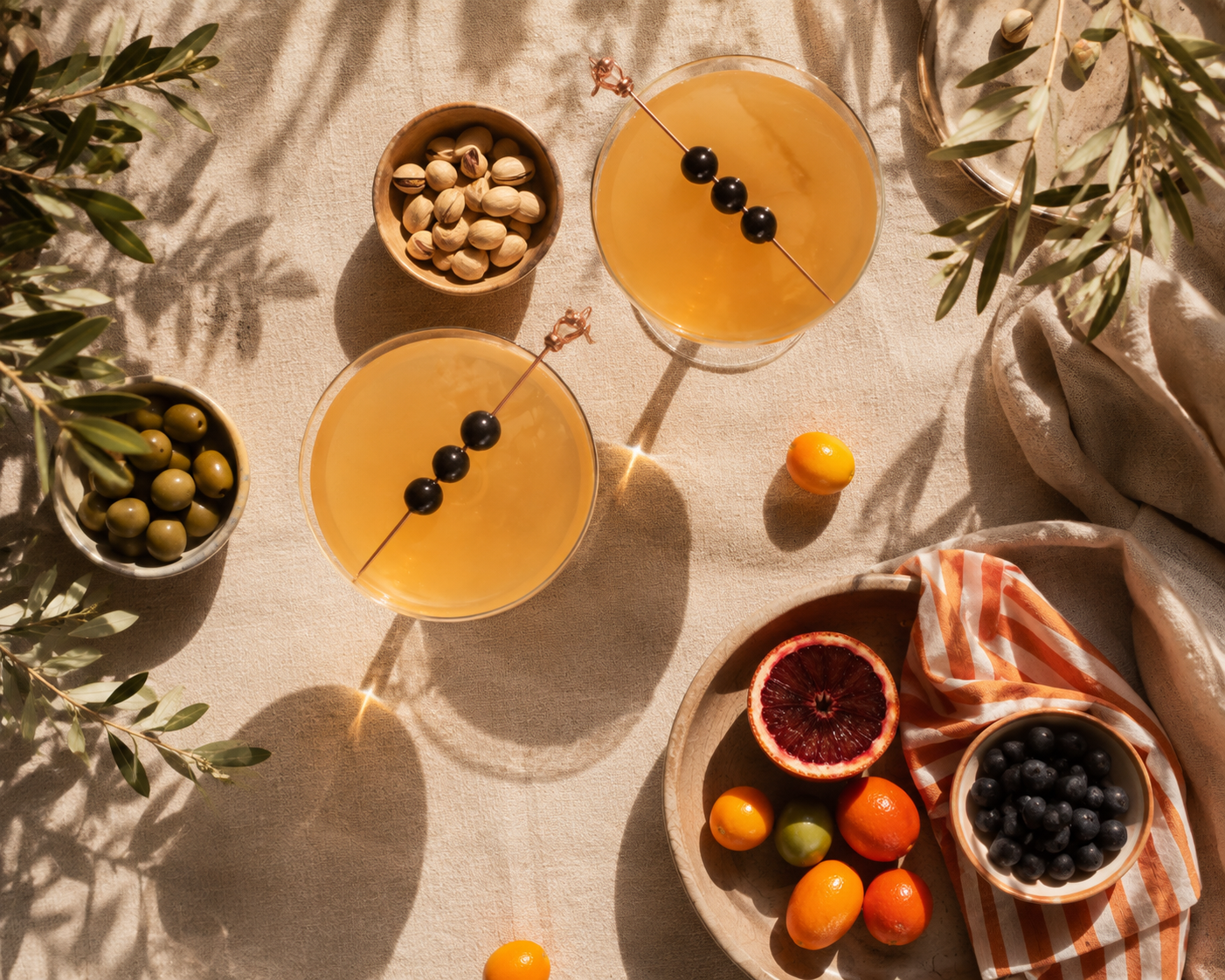 Cocktails, olives and citrus arranged on a linen tablecloth